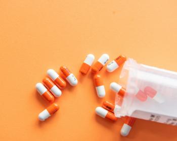 orange and white pills in a bottle on an orange surface